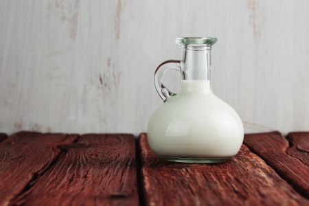 Glass of milk standing on old wooden table の写真素材