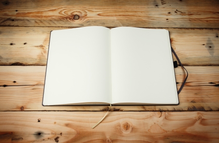 Open blank notepad with empty white pages  laying on a wooden table