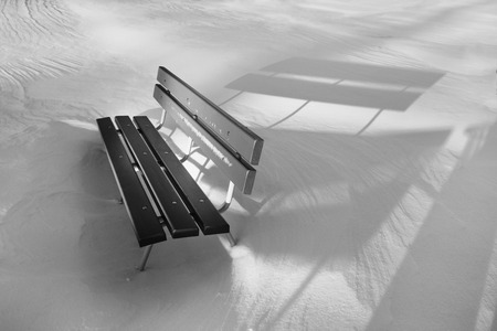 Wooden bench in snowy white landscape の写真素材