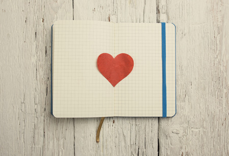 Blank notepad with red heart on wood table の写真素材