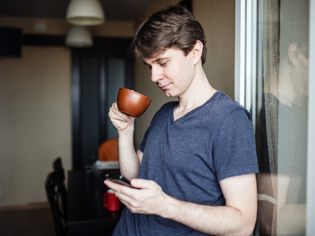 Man drinking coffee and using mobile smartphoneの写真素材