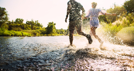 Happy couple running in shallow water. Summertime.の写真素材