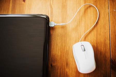 Laptop and modern mouse on wooden desk の写真素材