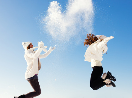 Two girlfriends have fun and enjoy fresh snow at beautiful winter dayの写真素材