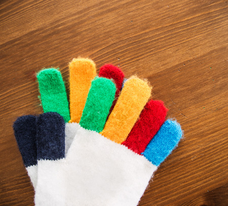 Pair of multicolor children's gloves on wooden tableの写真素材