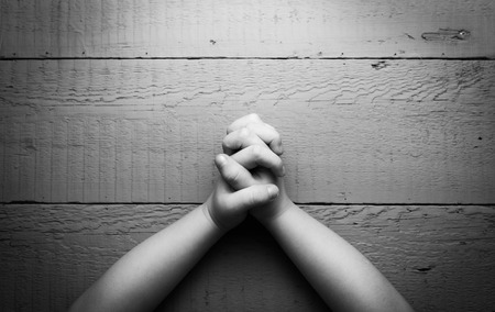 Child's hands folded together in prayer. Black and white photoの写真素材
