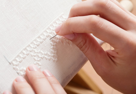 Woman hands doing cross-stitch. A close up of embroidery.の写真素材