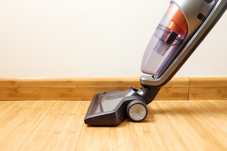Cordless vertical vacuum cleaner cleaning parquet floor.の写真素材