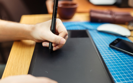 Close-up of a man's hand with a pen stylus, drawing on a graphic tabletの写真素材