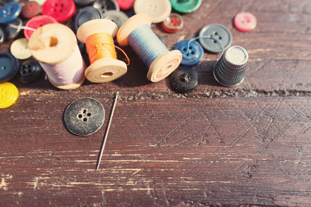 Spools of threads and buttons on old wooden table