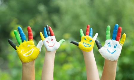 Colored hands with smile painted in colorful paints against green summer background. Lifestyle conceptの写真素材