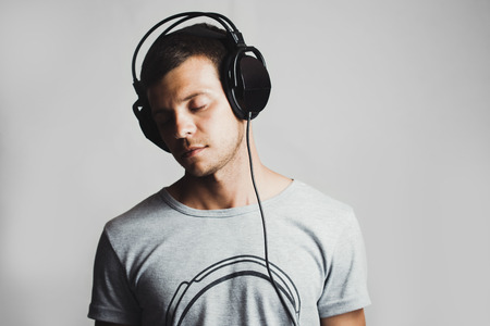 Portrait of a man listening to music on headphones, gray backgroundの写真素材