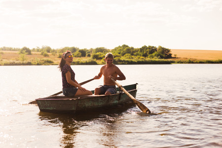 Happy romantic couple rowing a boat on lake.の写真素材