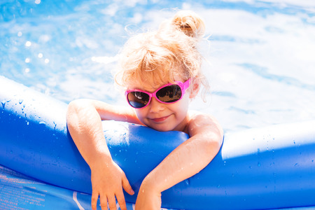 Happy girl playing in blue swimming pool. Summer holidays.の写真素材