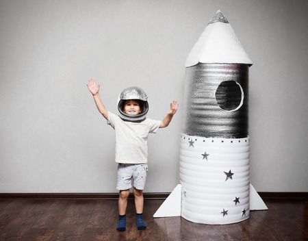 Happy child dressed in an astronaut costume playing with hand made rocket.の写真素材
