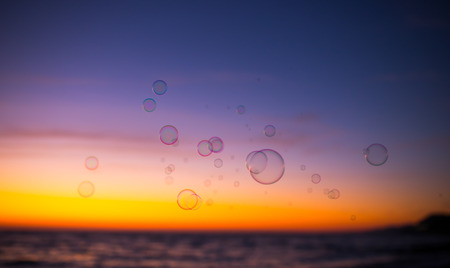 Background with soap bubbles floating in the sunset skyの写真素材