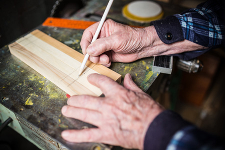 Old carpenter taking measurement of a wooden plankの写真素材