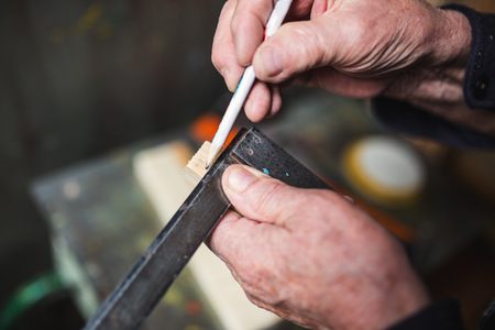 Old carpenter taking measurement of a wooden plank