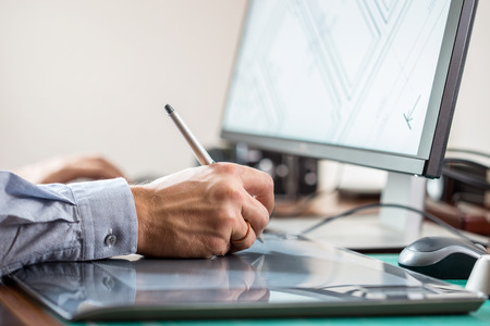 Graphic artist using graphics tablet at his desk