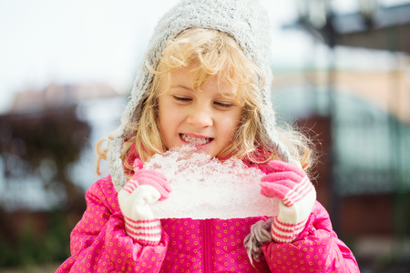 Portrait happy girl with piece of ice in handの写真素材