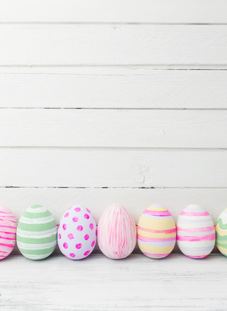 Easter eggs painted in pastel colors on white wooden background. Easter conceptの写真素材