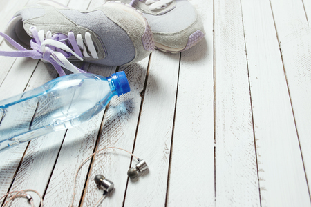Pair of sport shoes, water bottle and earphones on white wooden backgroundの写真素材