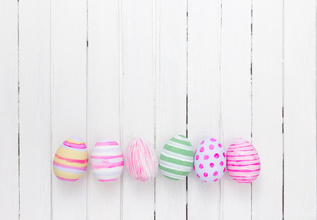Easter eggs painted in pastel colors on a white wood backgroundの写真素材