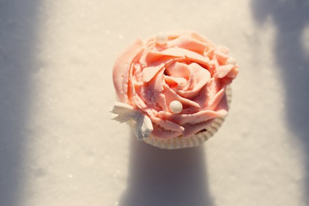 Outdoor photo of cupcake decorated with a sugar butterfly. Cupcake standing on fresh snow at sunny winter day.の写真素材