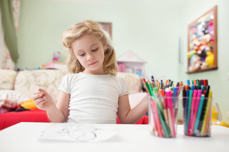 Portrait of child blonde girl drawing at home in her room.の写真素材