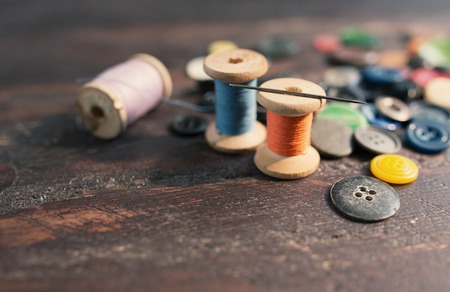 Spools of threads and buttons on old wooden table.の写真素材