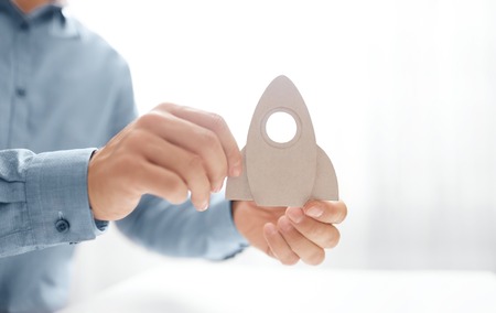 Man holding in hand a paper rocket . Startup, success and growth  business  concept. Rocket science...