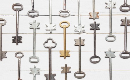 Some door keys aligned on old wooden surface, safety and security concept background.