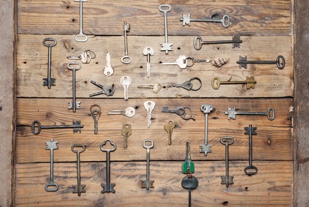 Some door keys aligned on old wooden surface, safety and security concept background.の写真素材