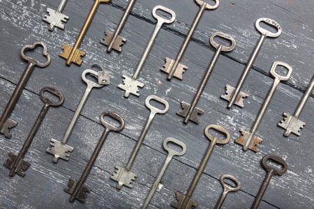 Some door keys aligned on old wooden surface, safety and security concept background.の写真素材