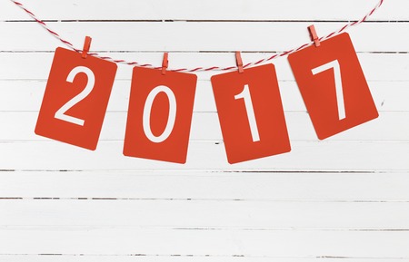 Paper or photo frames with 2017 figures hanging on the red striped rope . New Year design.  On wooden backgroundの写真素材