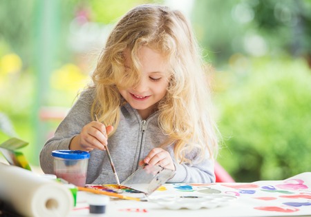 Portrait of little blonde girl painting, summer outdoor.の写真素材