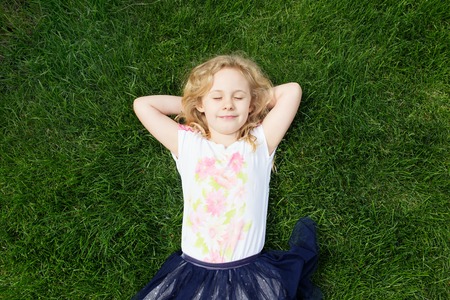 Dreaming adorable girl lying on grass, top view.の写真素材