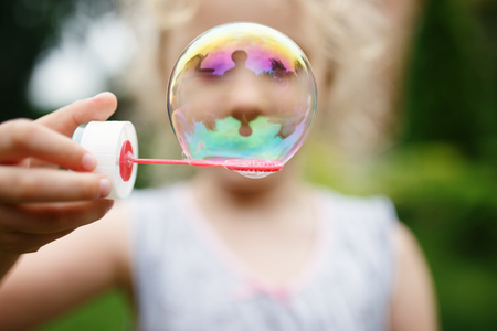 Cute little girl is blowing a soap bubbles and having fun.の写真素材