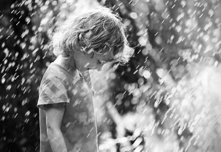 Photo of happy little girl standing under summer rain. Black and white.の写真素材