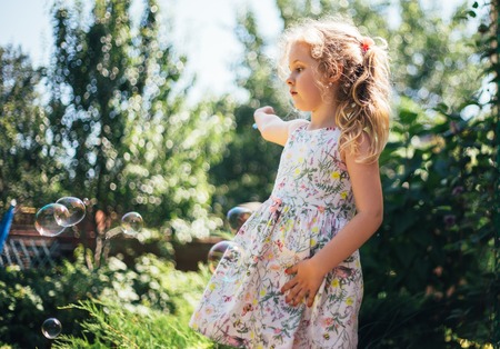 Cute little girl is blowing a soap bubbles and having fun.の写真素材