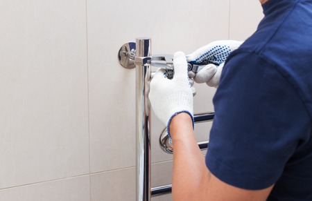 Plumber fixing chrome heated towel rail in bathroom.-の写真素材