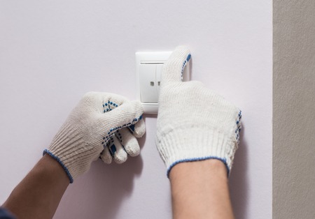 Electrician installing light switch, close up photo.