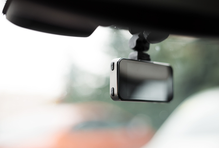 Car video recorder installed on front window, close up photo.