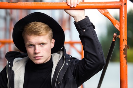 Young man posing with a black outfit against a urban background.の写真素材
