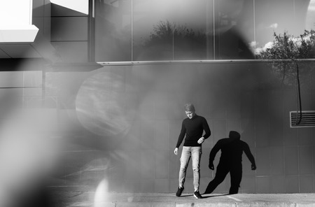 Black and white artistic photography. Young blonde man in black wear standing on street.