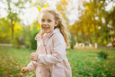 Happy child girl having fun in autumn park.の写真素材
