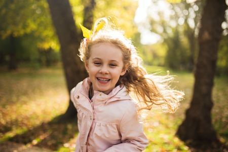 Happy child girl having fun in autumn park.の写真素材