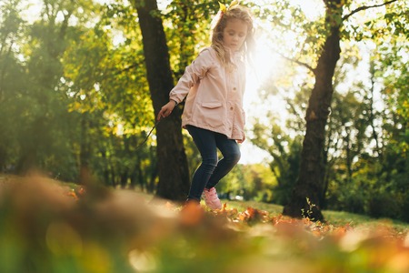 Happy child girl having fun in autumn park.の写真素材
