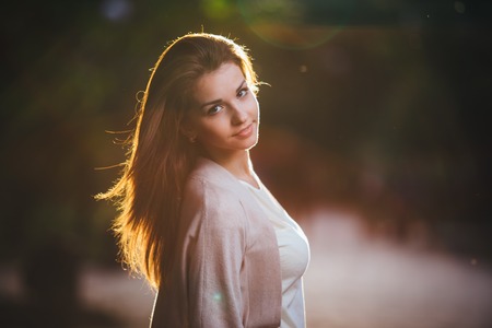 Portrait of beauty woman with perfect smile walking on the street and looking at camera. Sunset lightの写真素材
