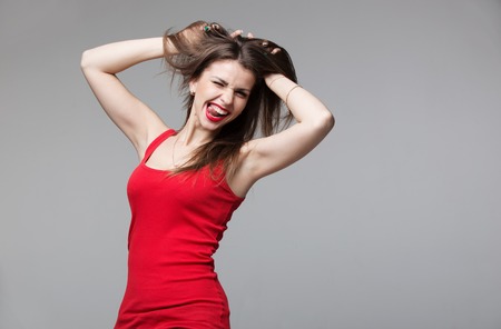Young brunette woman showing devil horns hand gesture posing in studioの写真素材